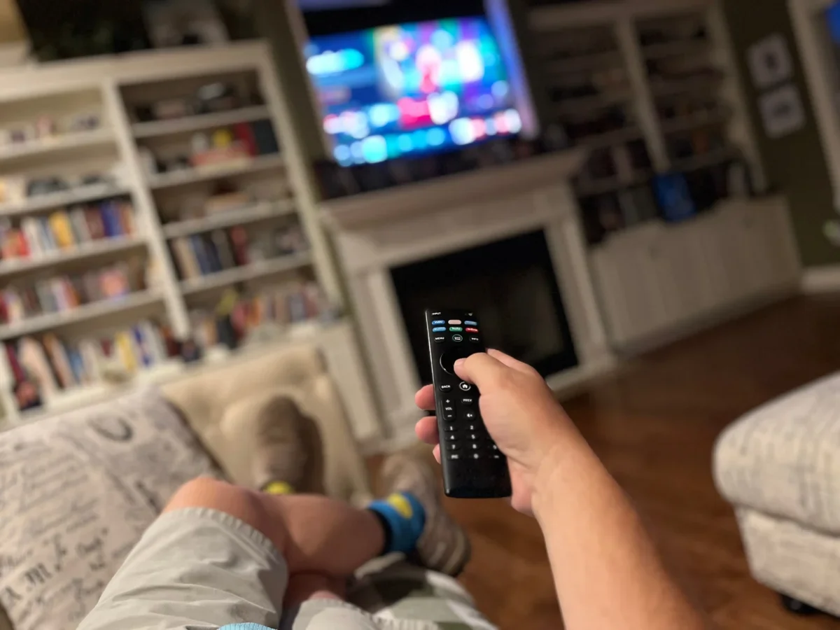 Muž ovladačem míří na televizi.