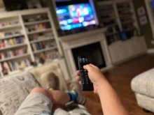 Muž ovladačem míří na televizi.