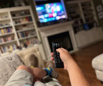 Muž ovladačem míří na televizi.