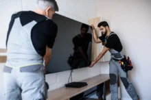 Muži instalují televizi na zeď.