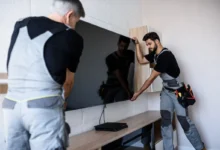 Muži instalují televizi na zeď.