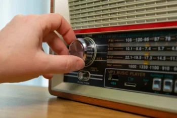 Close-up of a hand turning the chrome tuning knob on a vintage radio, with the FM/AM dial visible.