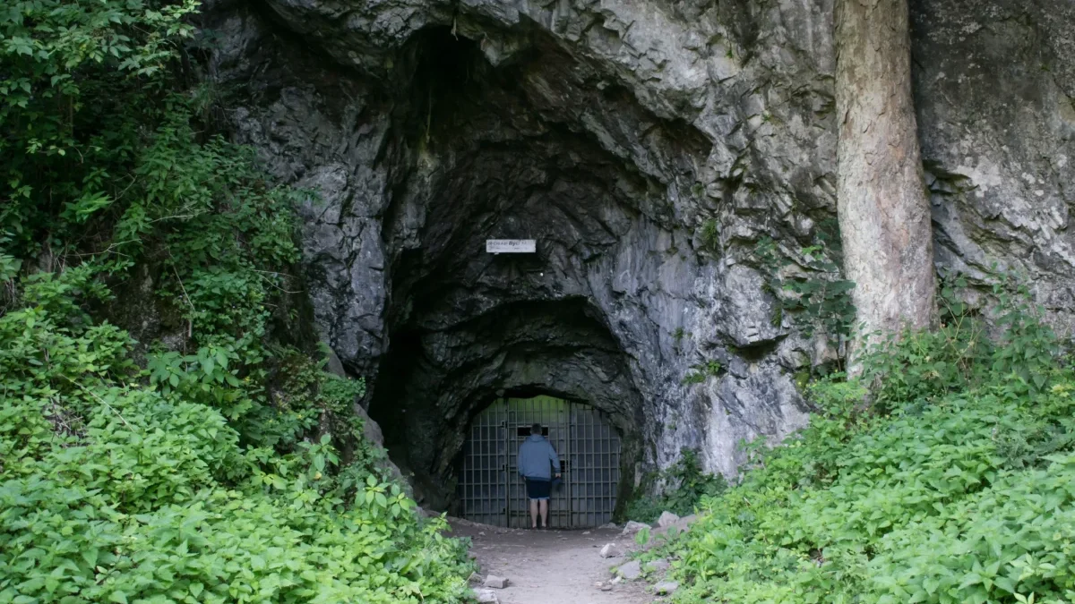 vstup do býčí skály, muž vchází do uzkého vchodu tohoto skalního masivu, který je obklopen zelení