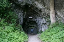 vstup do býčí skály, muž vchází do uzkého vchodu tohoto skalního masivu, který je obklopen zelení