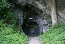 vstup do býčí skály, muž vchází do uzkého vchodu tohoto skalního masivu, který je obklopen zelení