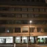 Nighttime view of a beige multi-story building with large windows and the sign 'Český Rozhlas' on the facade.