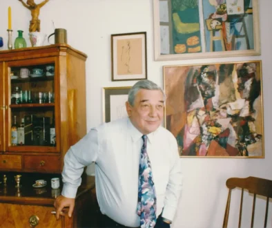 Josef Vinklář stojí u skříně.