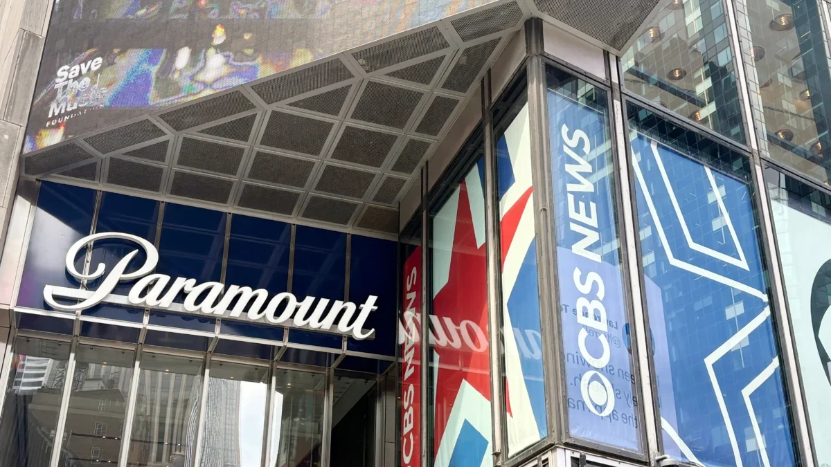 Glass-fronted building with large blue banners reading 'Paramount' along the windows and a metal, paneled overhang above the entrance showing a colorful mural.