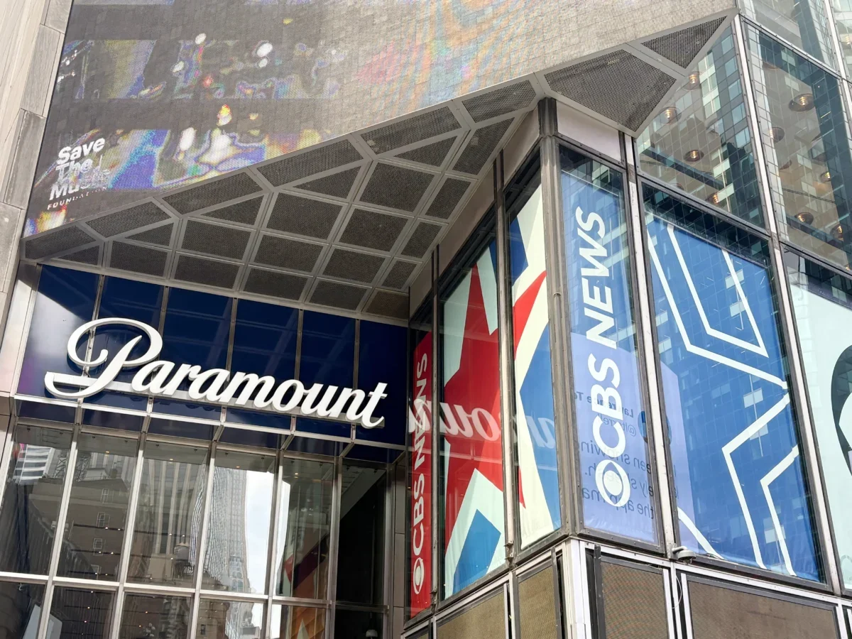 Glass-fronted building with large blue banners reading 'Paramount' along the windows and a metal, paneled overhang above the entrance showing a colorful mural.