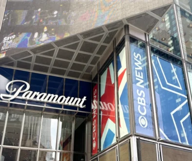 Glass-fronted building with large blue banners reading 'Paramount' along the windows and a metal, paneled overhang above the entrance showing a colorful mural.