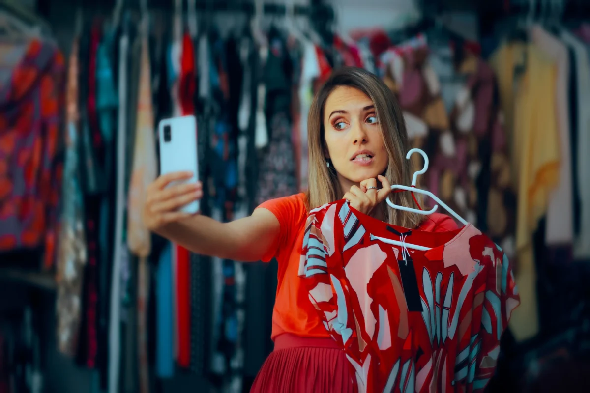 Žena fotící selfie se šaty v obchodě