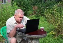 Senior sedí u notebooku.