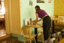servírka uklízí stůl v restauraci v Praze