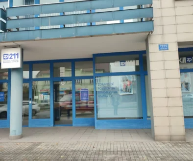 Blue-framed storefront of a Czech health insurance office (ZP 211) with glass doors and a street address plaque reading 1225 Wonkova on a beige tiled wall