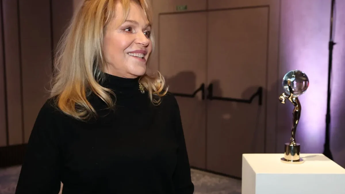 blonďatá žena v černém roláku vedle sošky