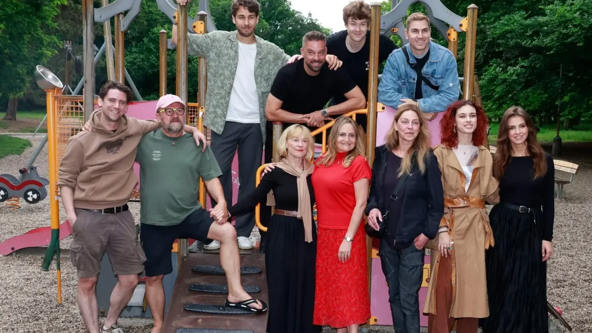 Group of adults posing on a colorful playground structure outdoors in a park.