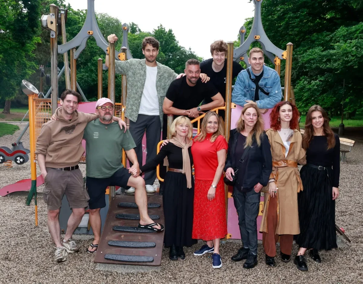 Group of adults posing on a colorful playground structure outdoors in a park.