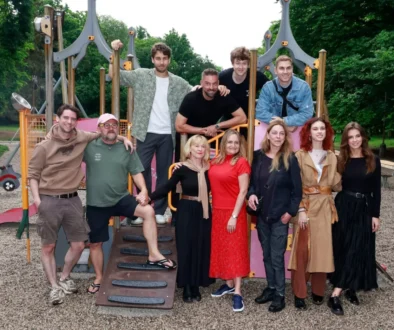 Group of adults posing on a colorful playground structure outdoors in a park.