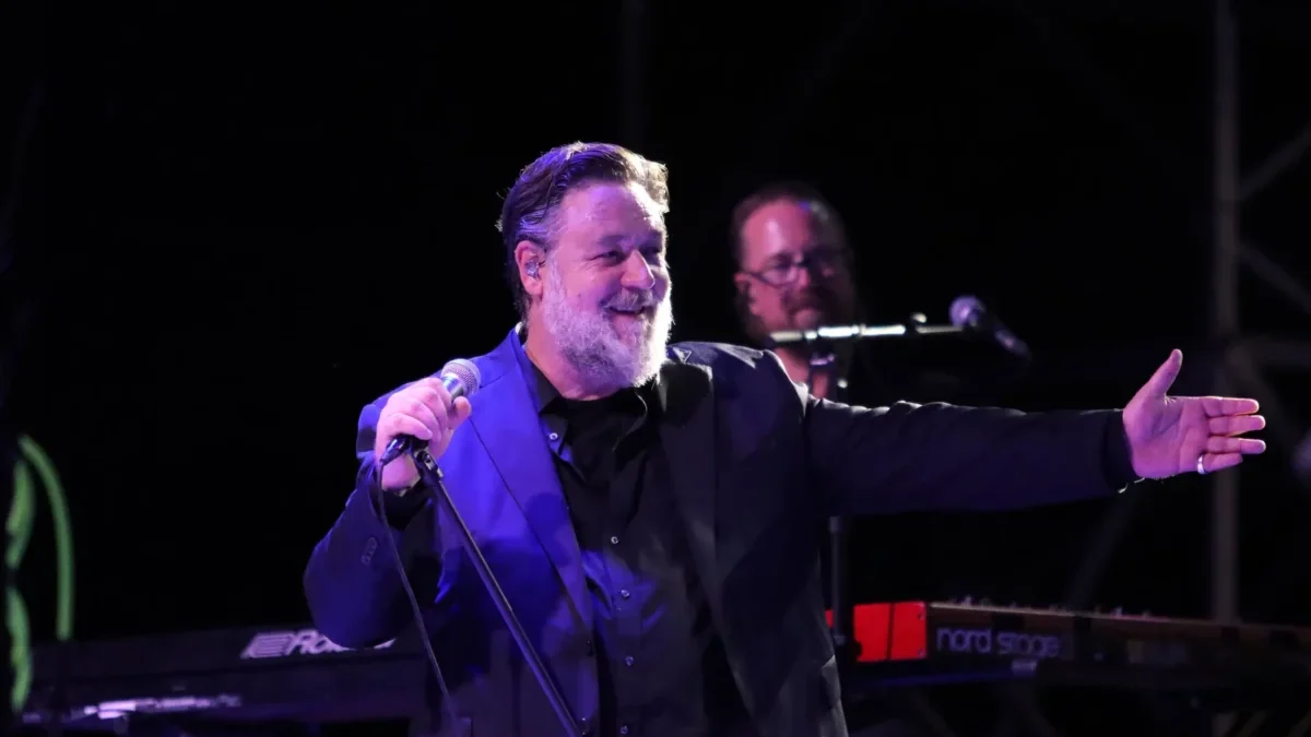 herec russell crowe ve smokingu mluvící do mikrofonu na podiu