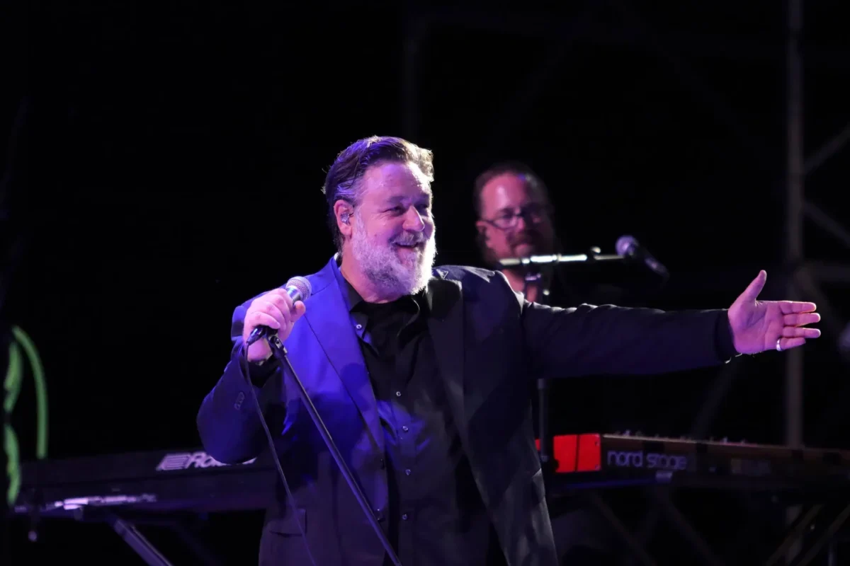 herec russell crowe ve smokingu mluvící do mikrofonu na podiu