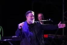 herec russell crowe ve smokingu mluvící do mikrofonu na podiu