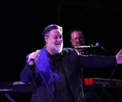 herec russell crowe ve smokingu mluvící do mikrofonu na podiu