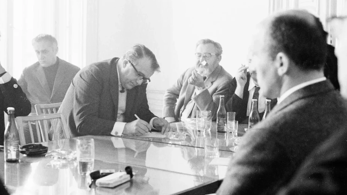 Jan Werich s dalšími lidmi sedí u stolu.