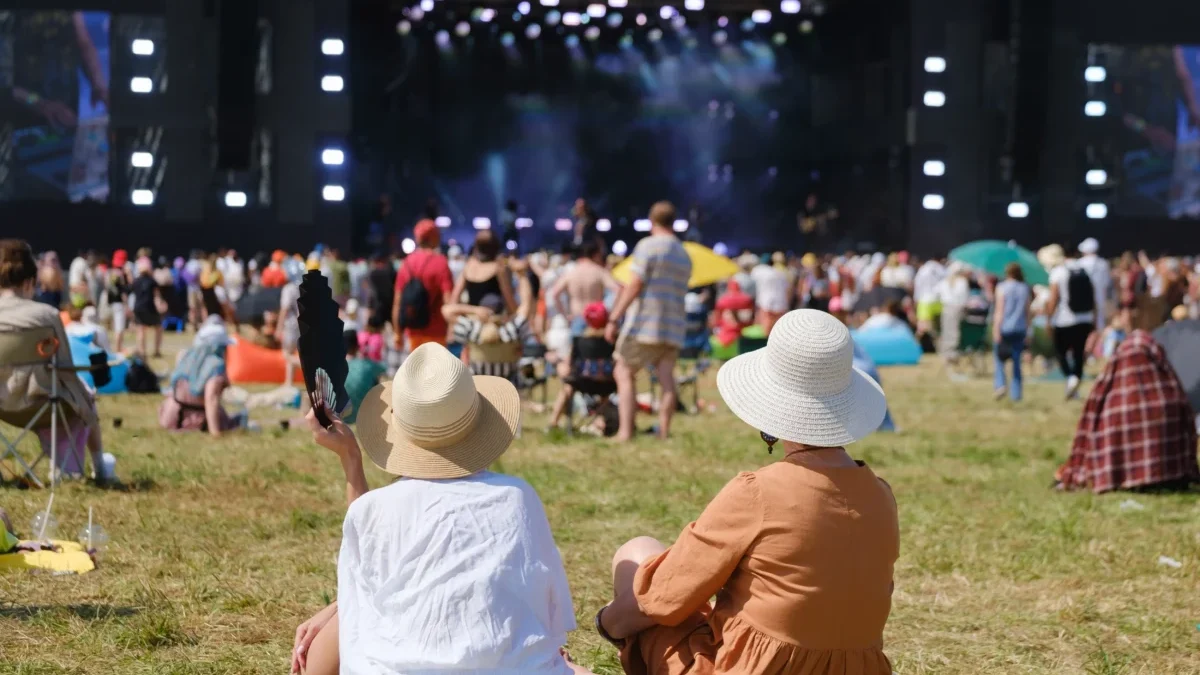Lidé sedí na festivalu na trávě.