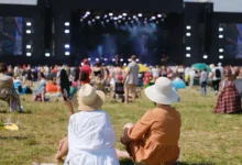 Lidé sedí na festivalu na trávě.