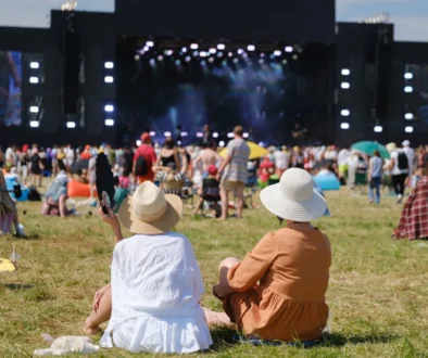 Lidé sedí na festivalu na trávě.