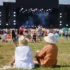 Lidé sedí na festivalu na trávě.
