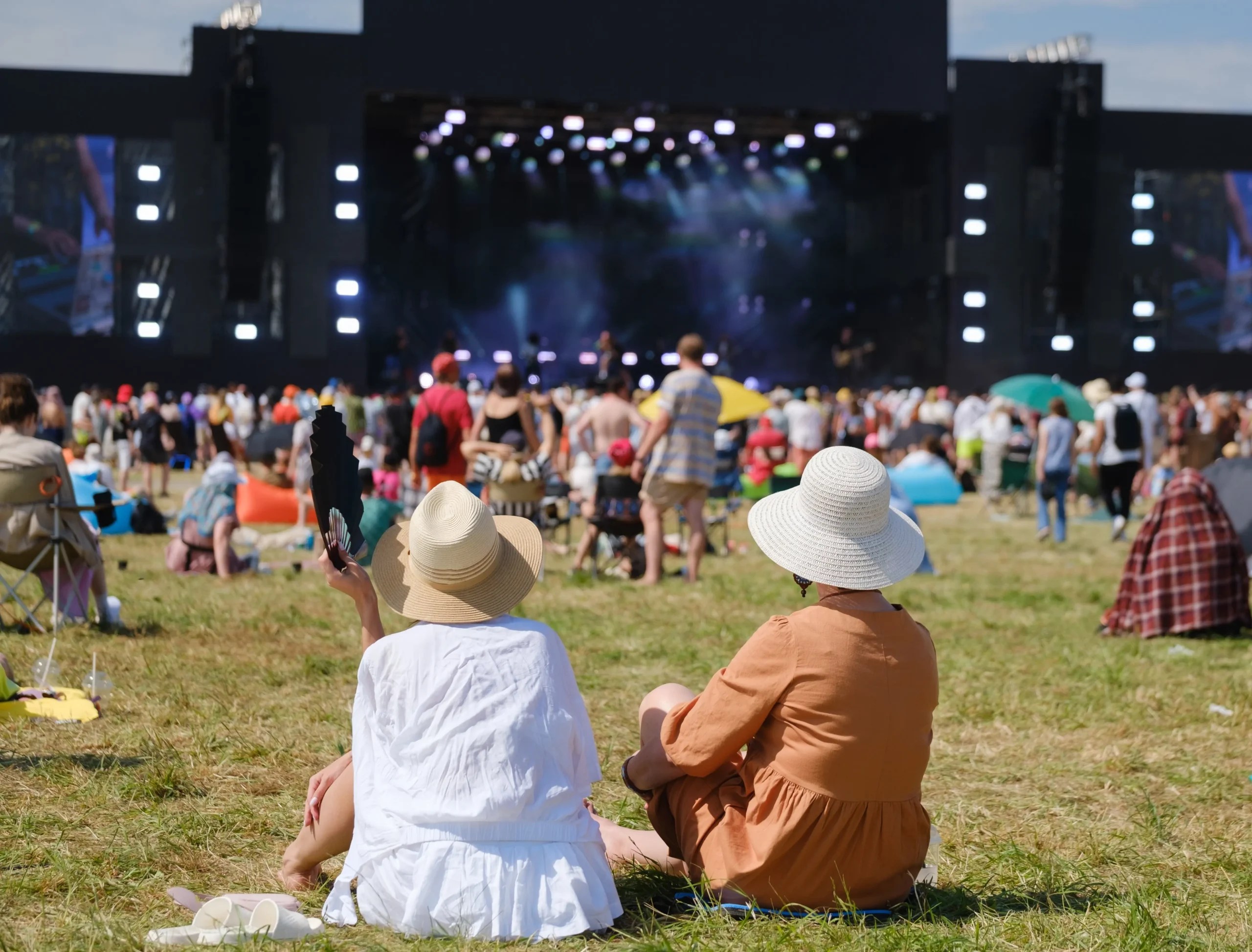 Lidé sedí na festivalu na trávě.