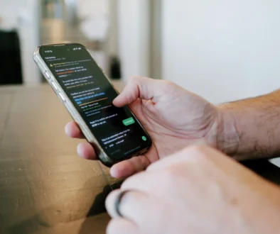 Ruka drží mobilní telefon se SMS zprávou