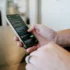 Ruka drží mobilní telefon se SMS zprávou
