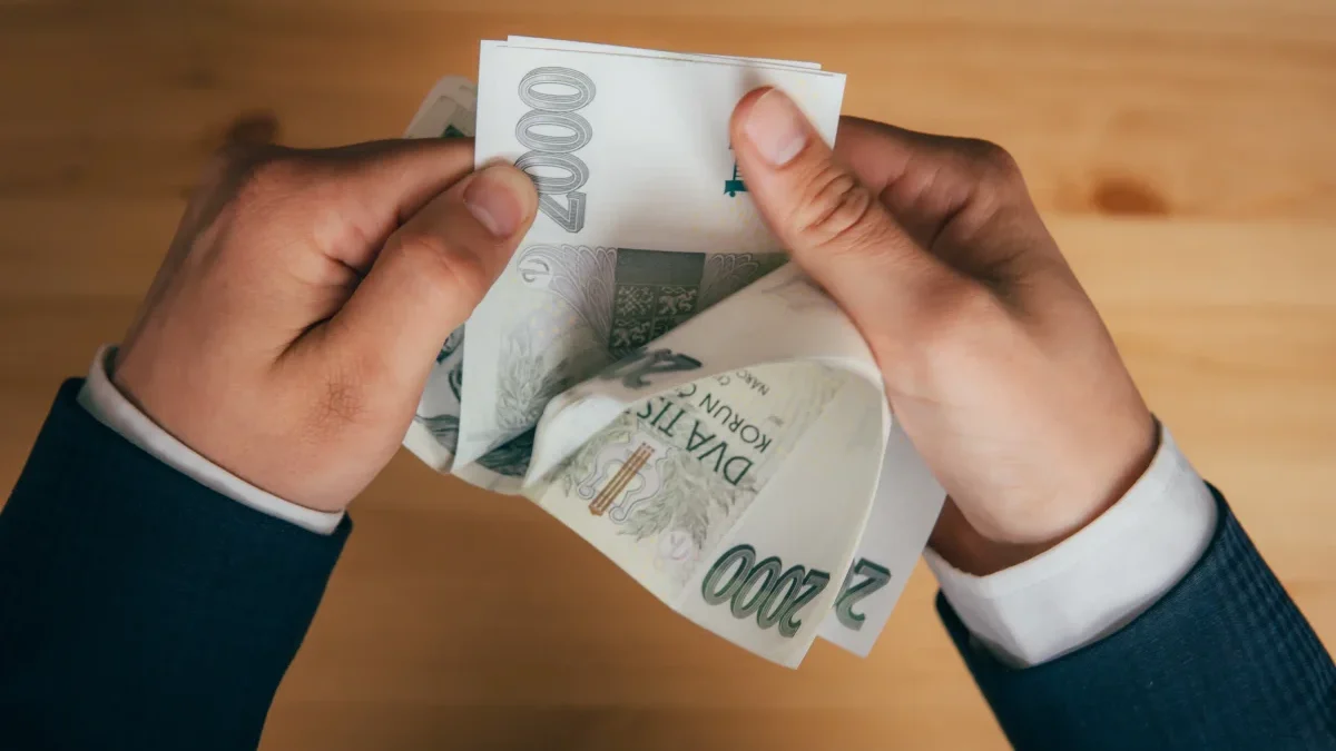 Muž držící v rukách české dvoutisícové bankovky
