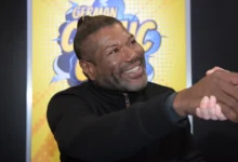 Christopher Judge si s někým třese rukou.