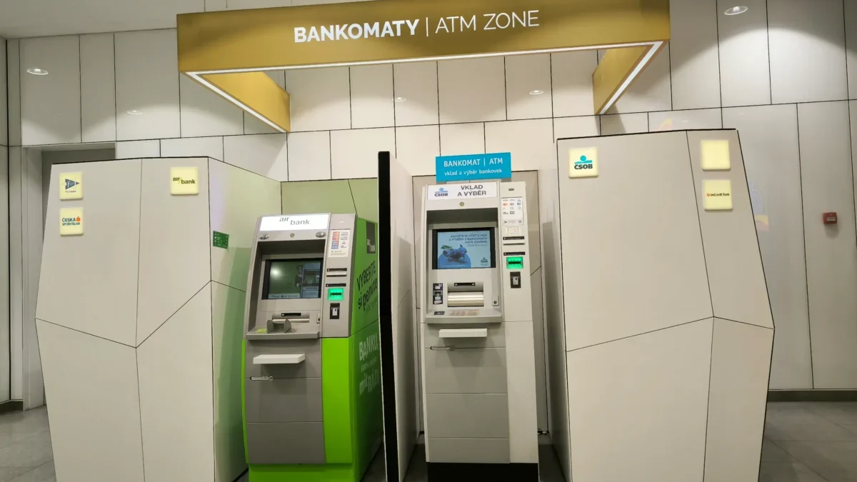ATM machines line a modern wall inside a bank, with a sign reading 'BANKOMATY | ATM ZONE' overhead