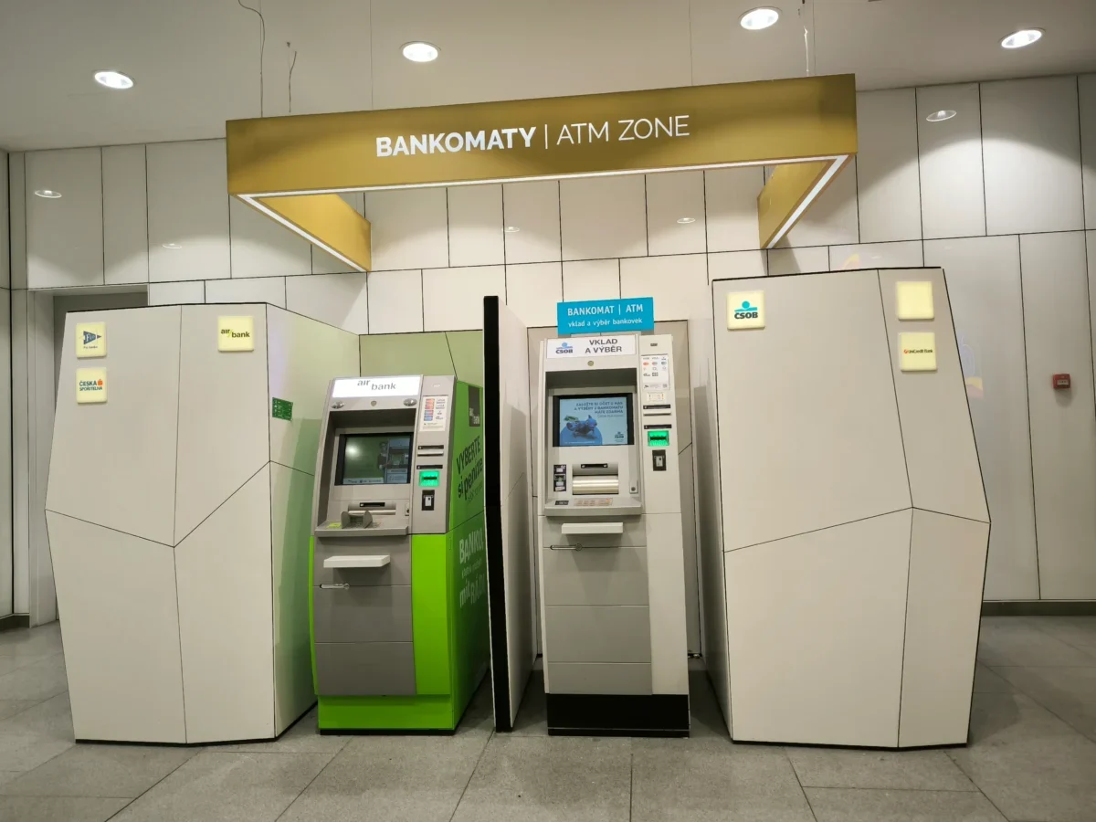 ATM machines line a modern wall inside a bank, with a sign reading 'BANKOMATY | ATM ZONE' overhead