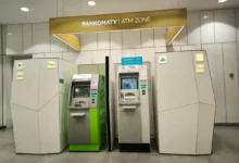 ATM machines line a modern wall inside a bank, with a sign reading 'BANKOMATY | ATM ZONE' overhead