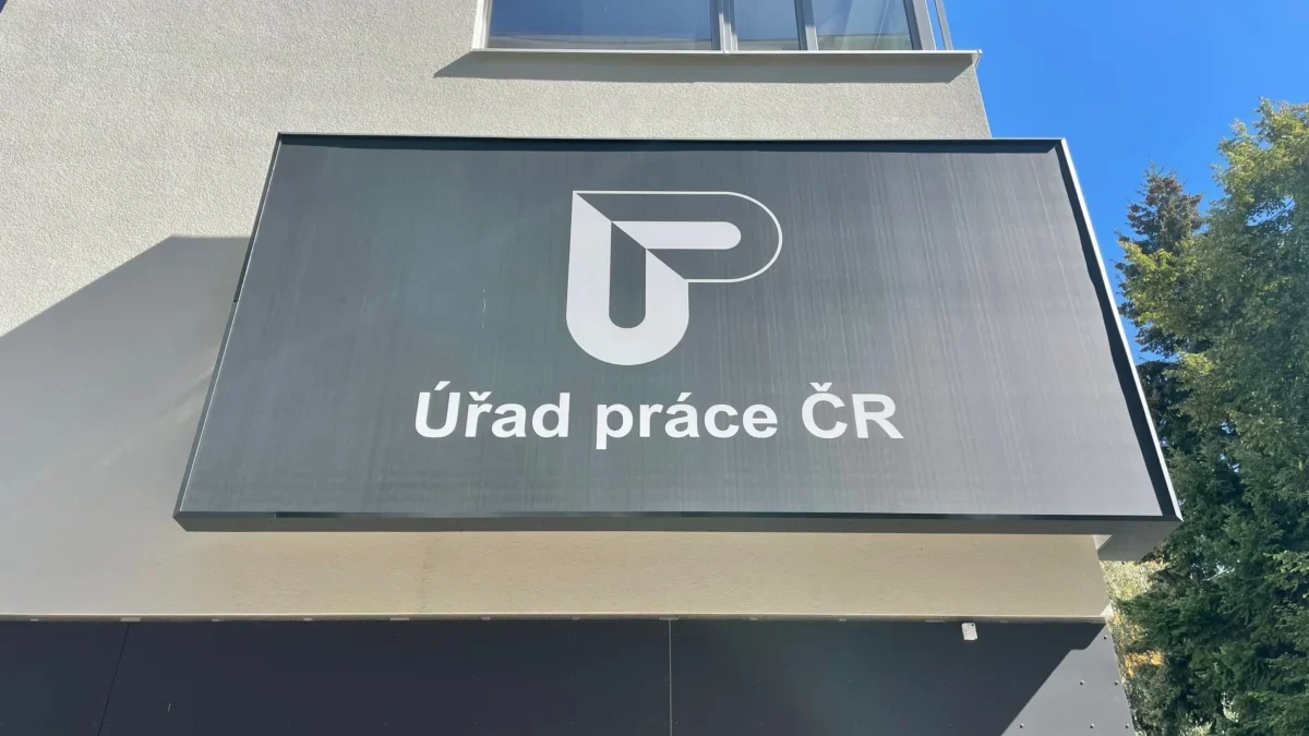 Signboard on a modern building reading 'Úřad práce ČR' with a white geometric logo on a dark panel.