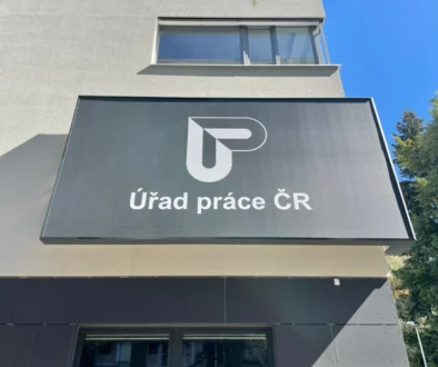 Signboard on a modern building reading 'Úřad práce ČR' with a white geometric logo on a dark panel.