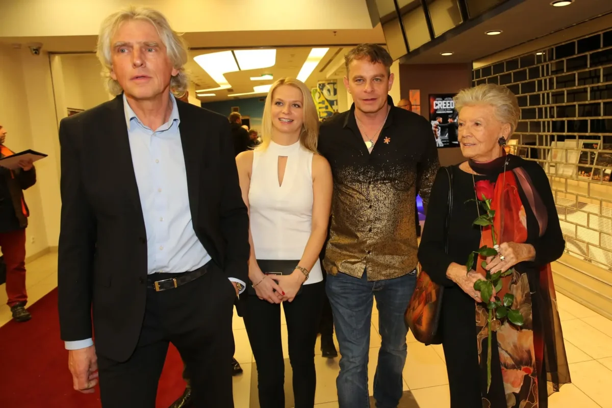 Zdenka Procházková stojí vedle lidí.