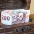 české bankovky vykukující z dřevěné truhličky