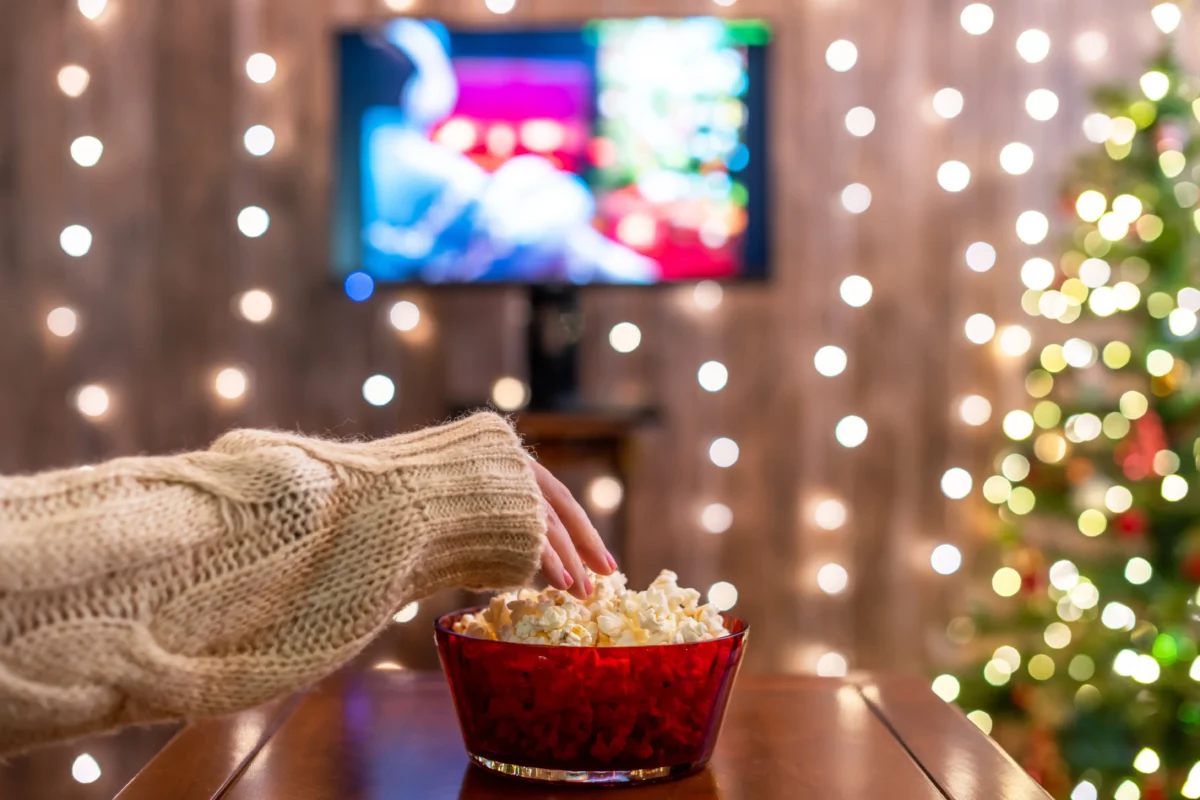 Ruka s miskou popcornu s vánočním zátiším u televize