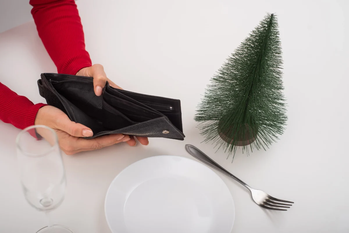 shutterstock_1873268599 | TVGURU.cz Žena drží u umělého stromku peněženku.