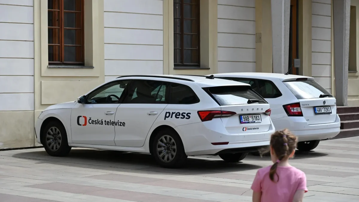 U budovy jsou zaparkovaná auta České televize.