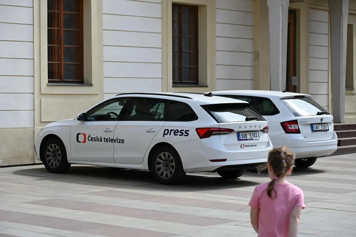 U budovy jsou zaparkovaná auta České televize.