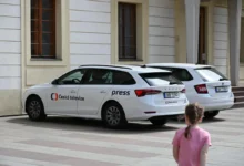 U budovy jsou zaparkovaná auta České televize.