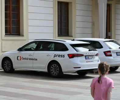 U budovy jsou zaparkovaná auta České televize.