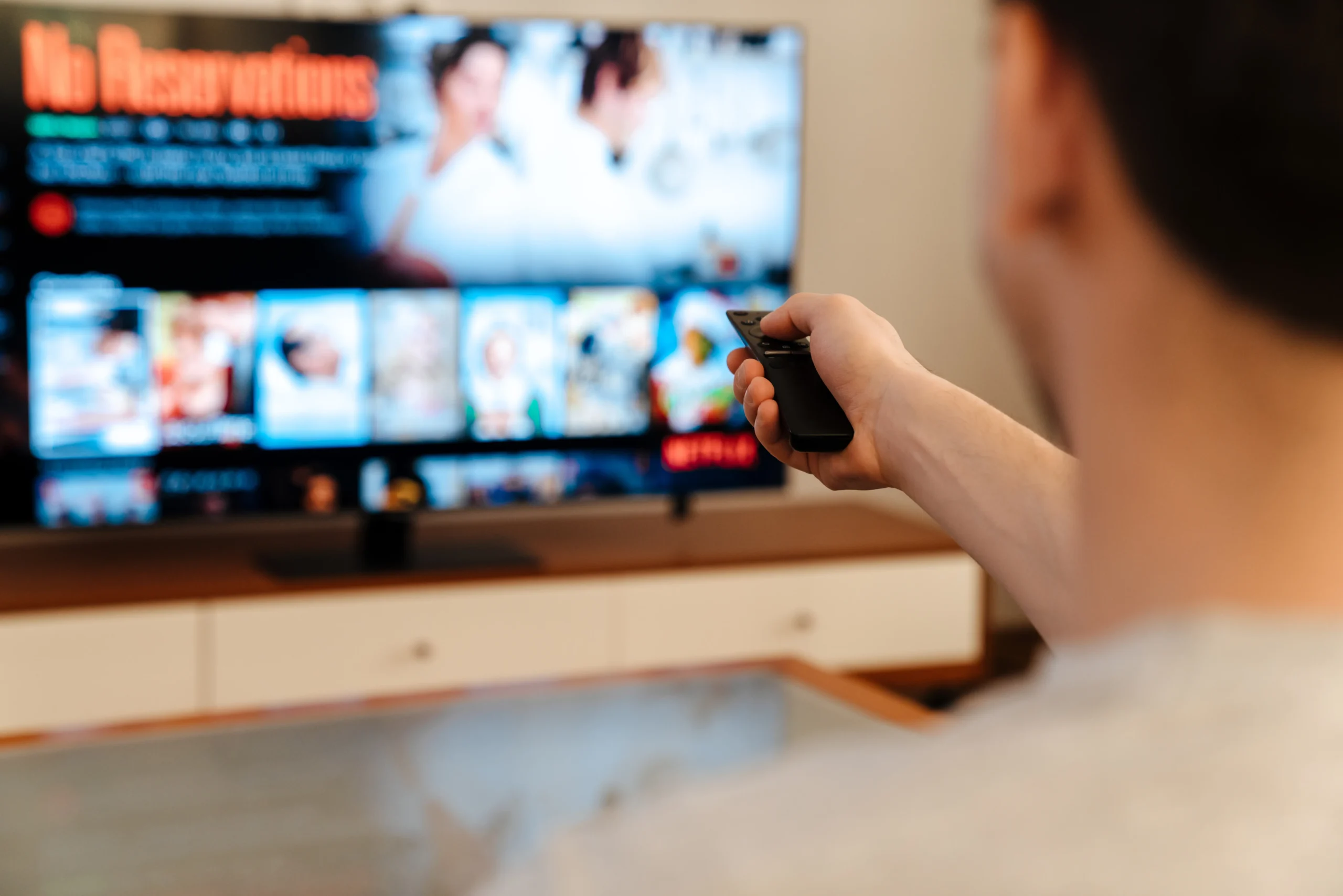 Člověk míří ovladačem na TV.